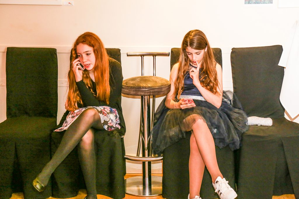 Two girls sitting on their phones at a party