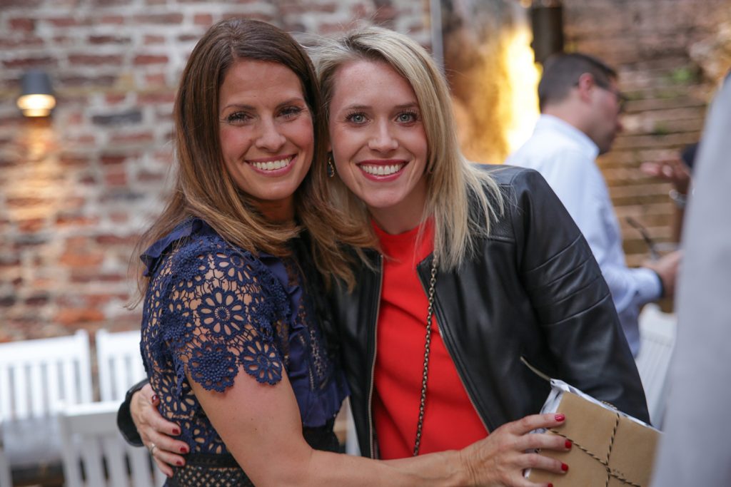Two women hugging and smiling into camera at party