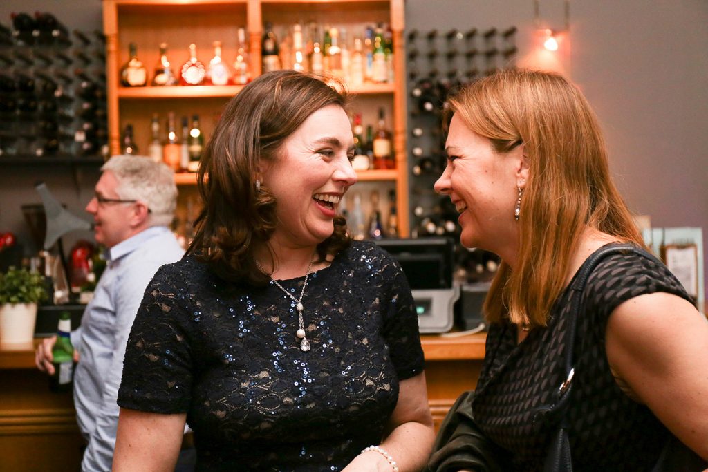 Two women laughing together at a bar