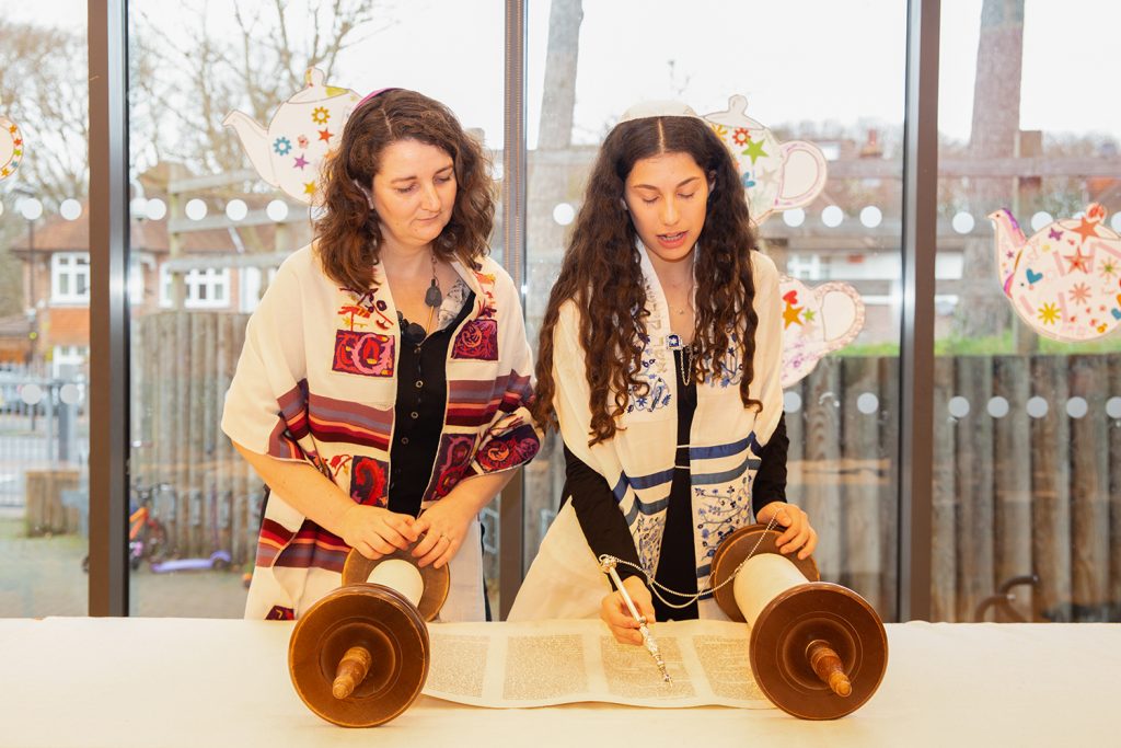 Barmitzvah girl reading the scroll next to lady rabbi