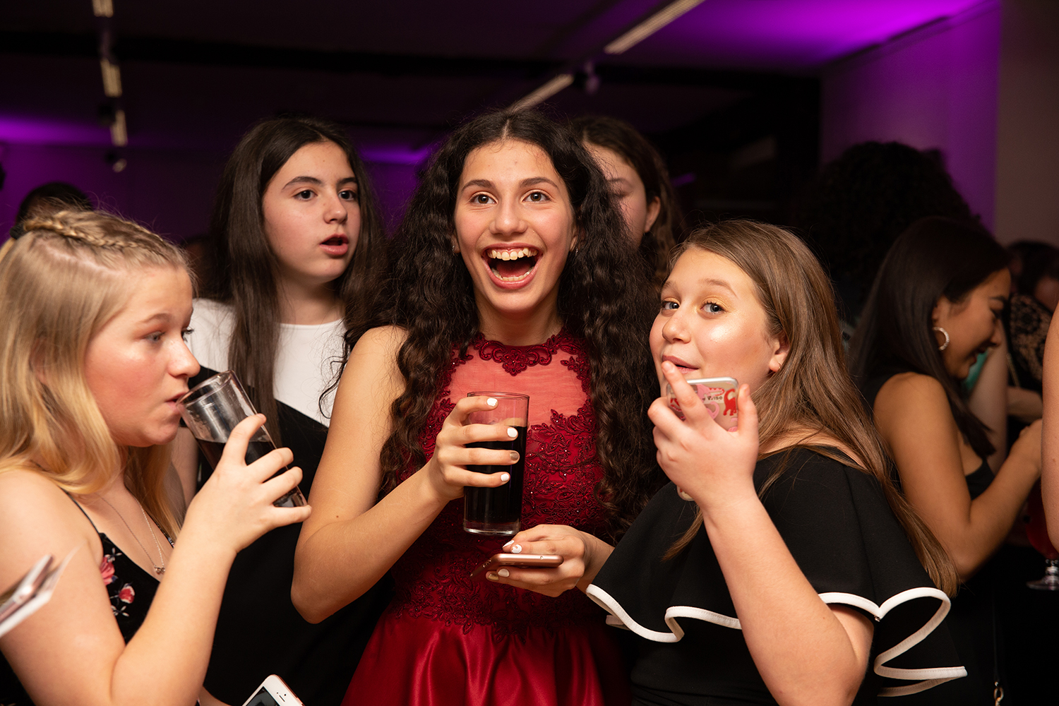 Girls laughing together drinking cokes at party