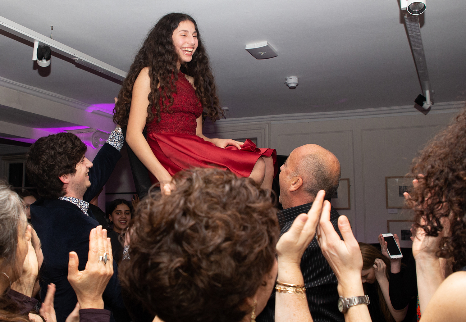 Girl in red dress being held up and danced around at party