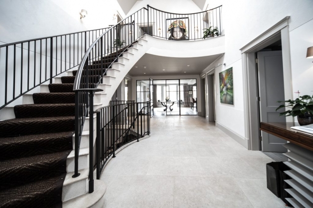 Huge hallway with big curved staircase and marble floodway