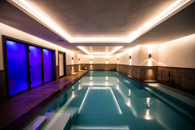 Indoor swimming pool with bright blue doors and down lights