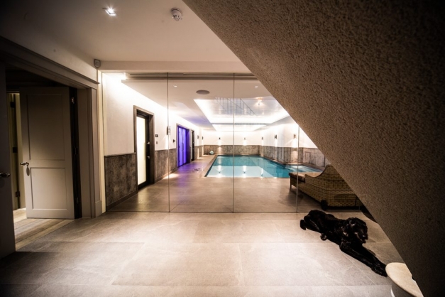 Indoor swimming pool with glass doors and sun loungers