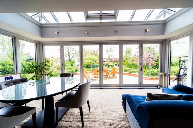 Big conservatory room with blue velvet sofa and dining table