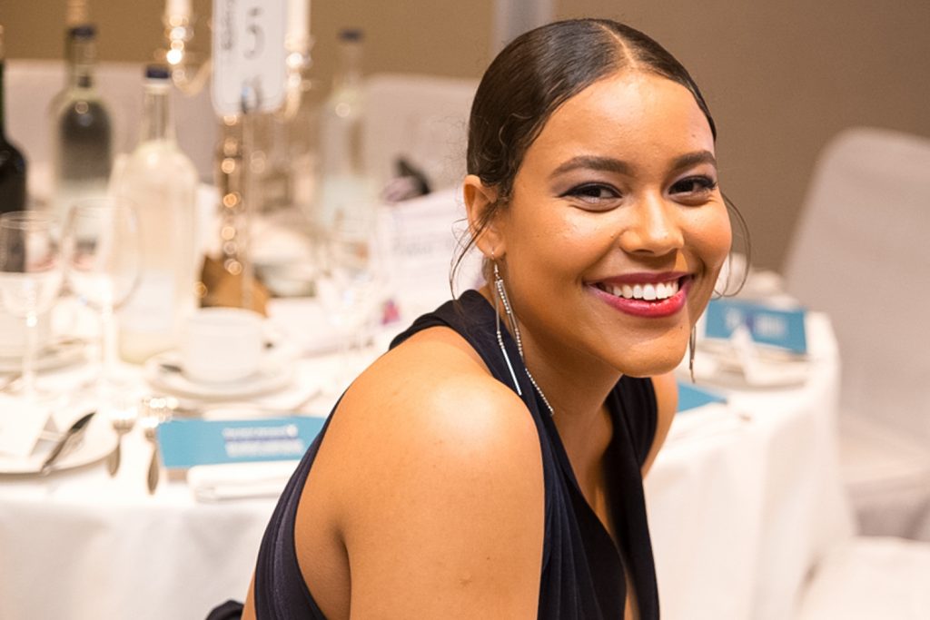 Lady smiling in blue dress sitting at a table at an event