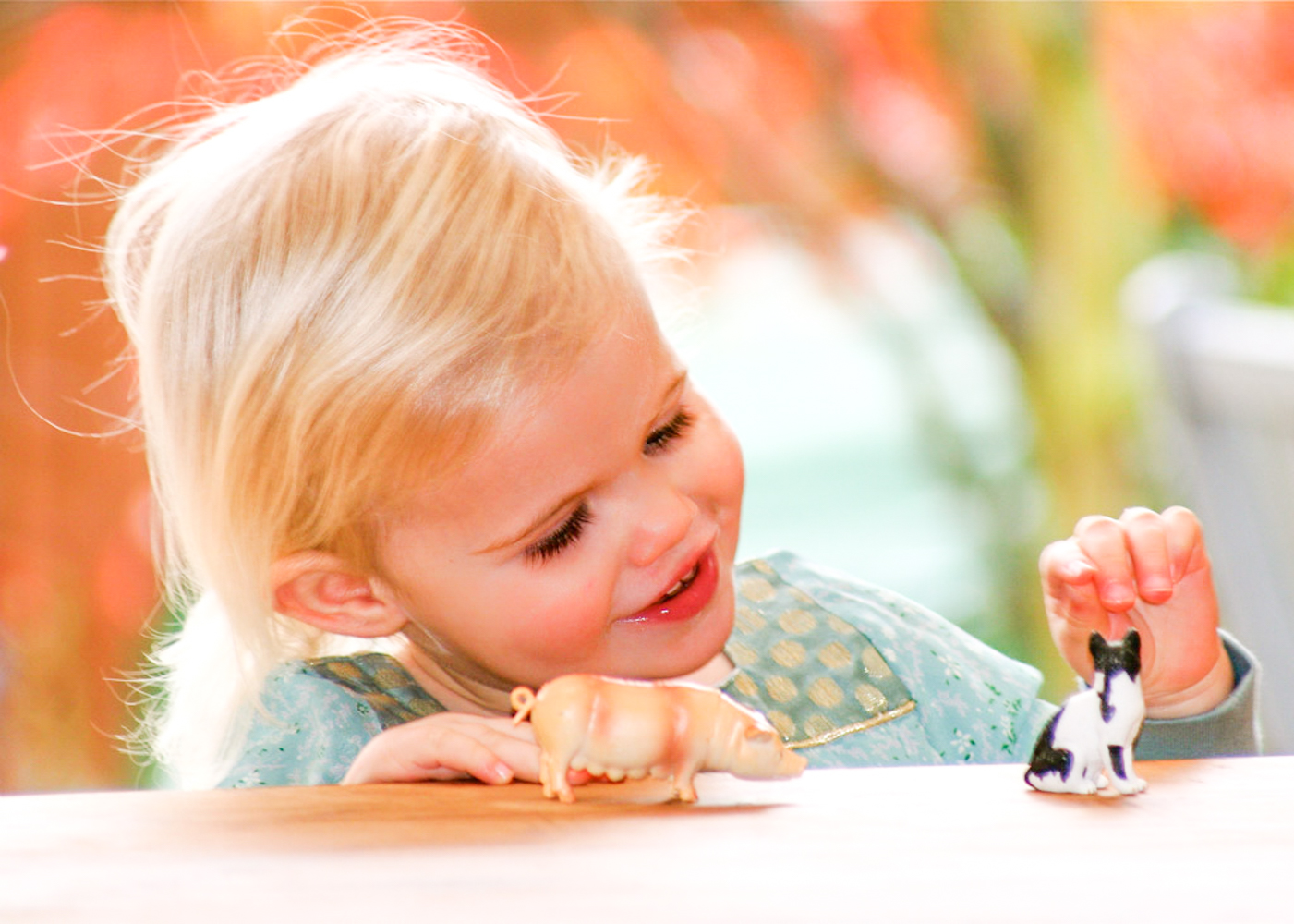 Pretty little blonde girl playing with toy animals