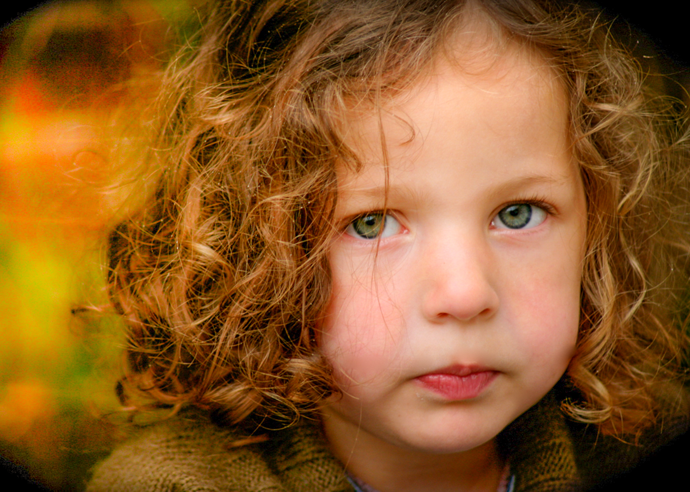 close up of young girl with green eyes and curly blond hair