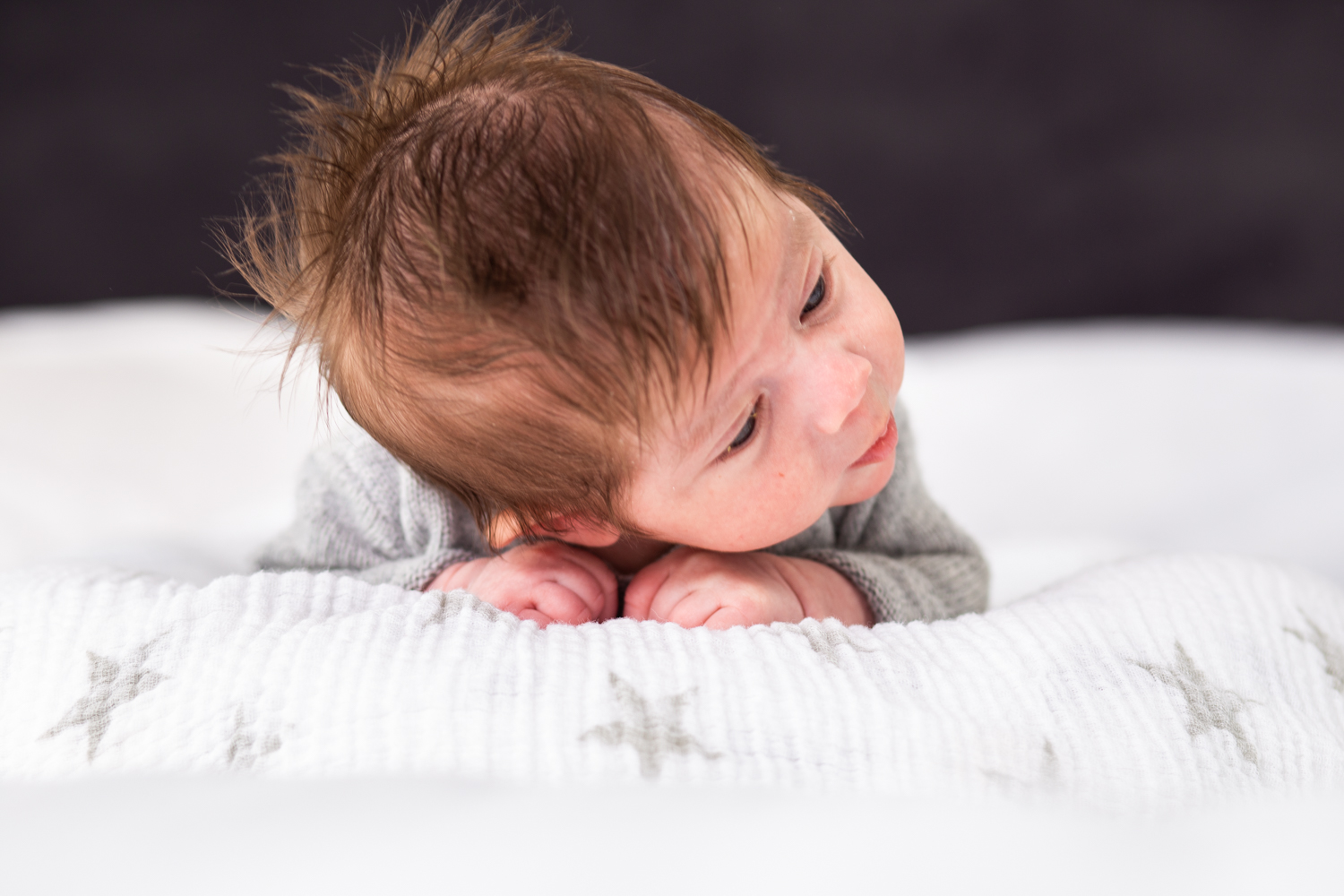 baby with lots of hair lying on white blanket