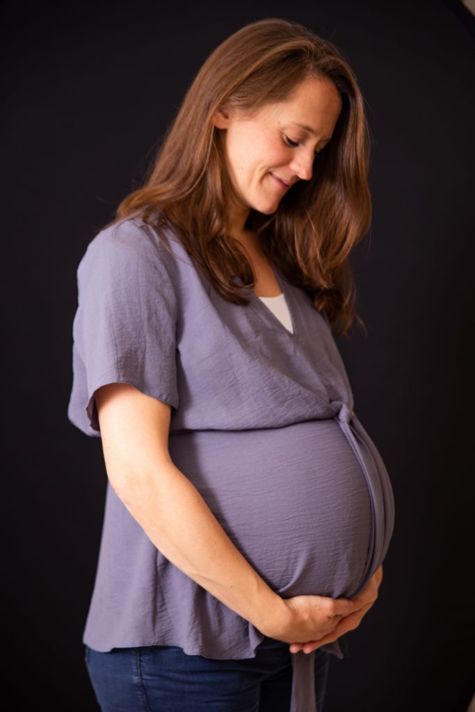 Pregnant woman holding her bump and smiling down at it